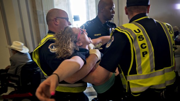 A demonstrator protesting cuts to Medicaid is carried away from the office of Senate Majority Leader Mitch McConnell at the Russell Senate Office building in Washington.
