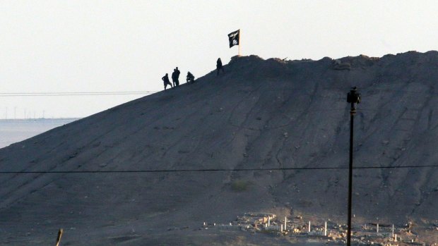 The black flag of Islamic State flies over the town of Kobane in Syria in October 2014.