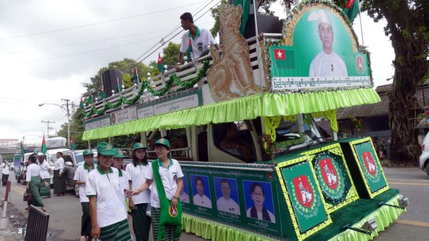 Members of military backed Union Solidarity and Development Party walk near a campaign truck displaying an image of Myanmar President Thein Sein on Thursday.