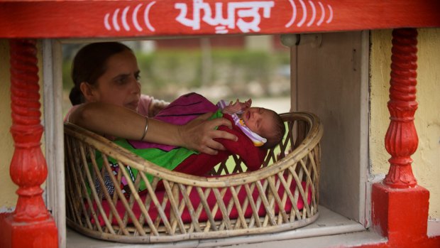 A baby girl left anonymously at Red Cross offices in Amritsar, Punjab, is removed form a basket.