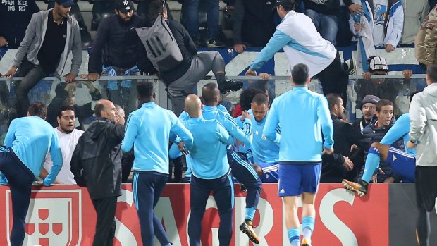 Marseille's Patrice Evra (centre) is dragged away by his teammates.
