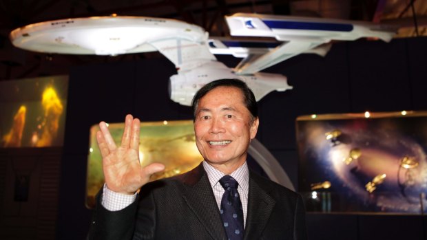George Takei, who played helm officer Sulu in  "Star Trek," gives a "live long and prosper" gesture in front of a model of the USS Enterprise, Tech Museum, San Jose, California.