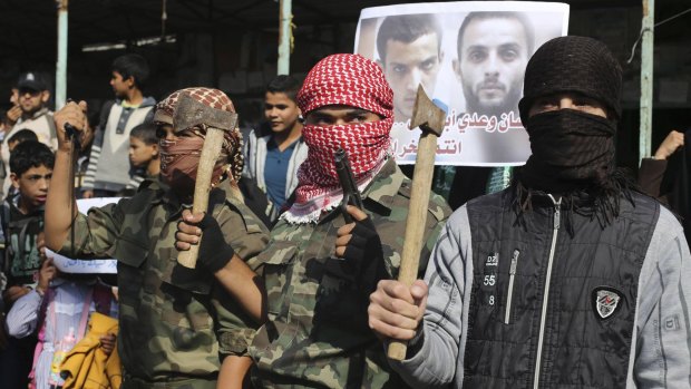 Masked Palestinians hold axes and a gun as they celebrate an attack on the Jerusalem synagogue on November 18.