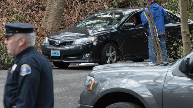 A US special agent checks a car with diplomatic licence plates as it drives out of the Russian compound in Upper Brookville, Oyster Bay, on Long Island  on Friday.