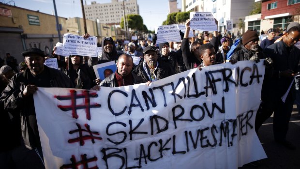 People walk through skid row in protest against the killing of a homeless man by police in Los Angeles. 
