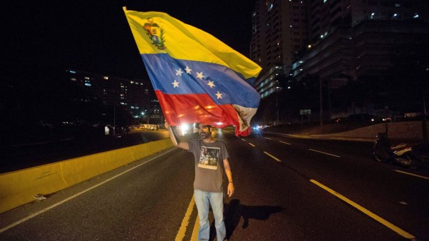 An opposition member waves a Venezuelan flag during a protest against President Nicolas Maduro in Caracas on Thursday.