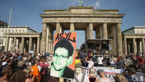 A protester carries a picture of Snowden with the German word for ''asylum'' during a 2013 protest in Berlin. 