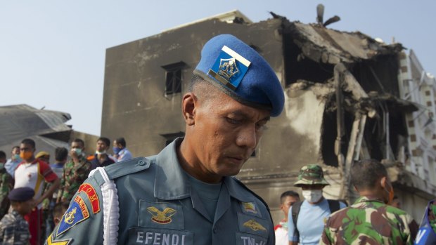 A member of the Indonesian Air Force looks over the wreckage of a military transport plane which crashed into a building on June 30, 2015 in Medan.