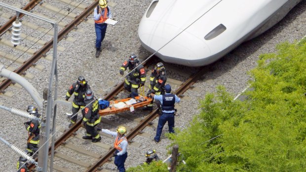 A passenger on the stretcher is carried by rescue workers from the train. 