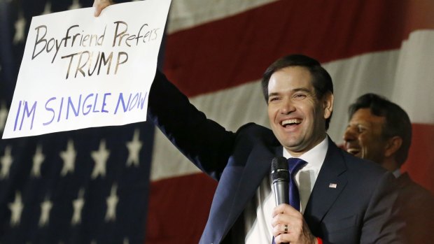 Republican presidential candidate Marco Rubio holds up an anti-Trump sign in Oklahoma on Monday.