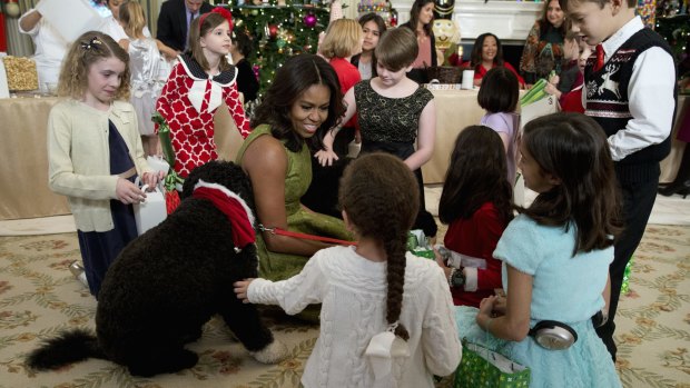 Michelle Obama with dogs Bo, left, and Sunny, behind at right, surrounded by children in the White House last year.