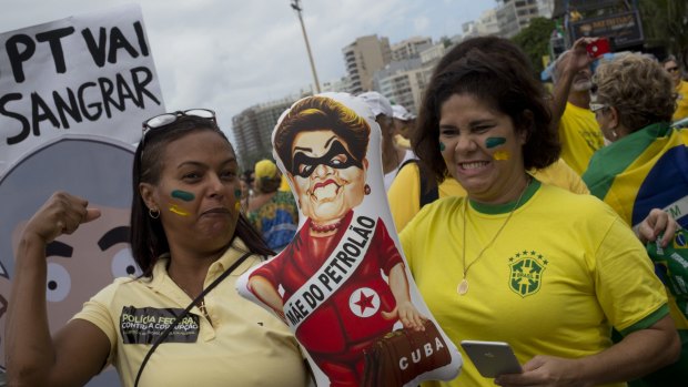 Demonstrators pretend to hit a doll depicting President Dilma Rousseff as a Cuba-sympathising oil revenue thief.