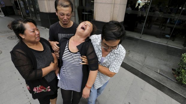 The mother (centre) of missing firefighter Xue Ning is helped by other family members as she cries after trying to demand more information from government officials.
