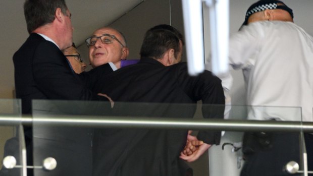 Police officers handcuff Michael Teplitsky (in glasses) during a scuffle amid a raid on his Double Bay office.
