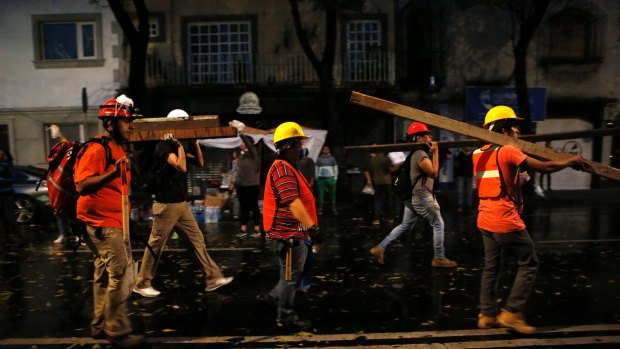 A group of men calling themselves the Insurgentes Brigade arrive carrying wood to offer their services at a site of earthquake damage in Mexico City.