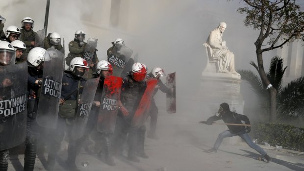 An anti-establishment protester tries to attack riot police during a protest against high-security prisons in Athens.