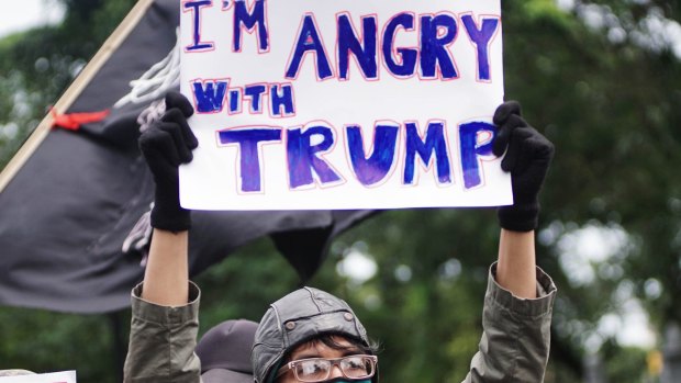 People hold placards during a protest against US President Donald Trump and his recent policies outside of the American Embassy in Jakarta.