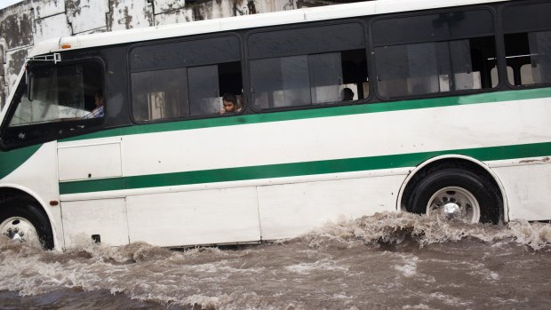 A child looks out of a city bus as it drives through a flooded road in Tecoman, Mexico.