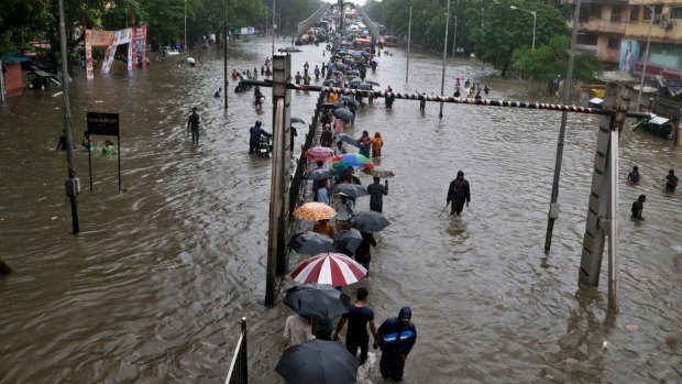 People walk through a waterlogged street following heavy rains in Mumbai, India, on Tuesday.