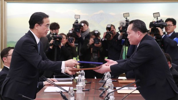 Ministers from North and South Korea exchange a joint press release following their first high-level talks in over two years.