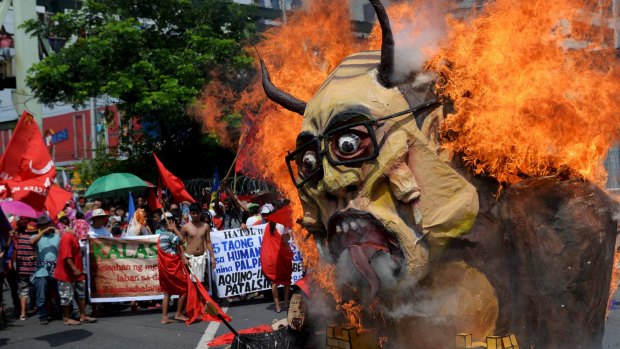 Protesters burn an effigy of President Benigno Aquino III during a rally in Manila on Monday.
