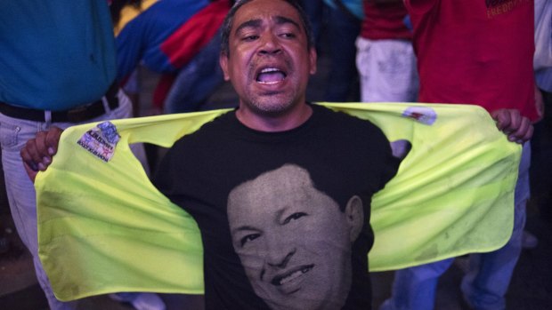 A supporter of the ruling United Socialist Party of Venezuela (PSUV) wearing a T-shirt bearing the image of late president Hugo Chavez shouts slogans outside the party's headquarters.