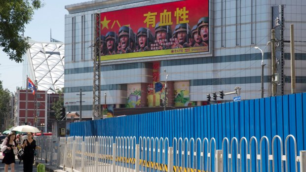 People walk near a billboard of the Chinese military reading "courageous", in Beijing, last month. Beijing is intensifying its warnings to Indian troops to get out of a contested region high in the Himalayas where China, India and Bhutan meet.