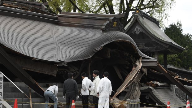 Staff of the historic Aso Shrine examine its gate collapsed by an earthquake in Aso, Kumamoto prefecture.