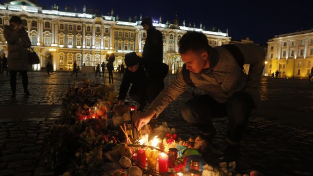 A man lights a candle in memory of the plane crash victims at Dvortsovaya Square in St. Petersburg, Russia, on Tuesday.