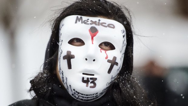 A person in a mask protests Mexican President Enrique Pena Nieto's presence in Washington DC.
