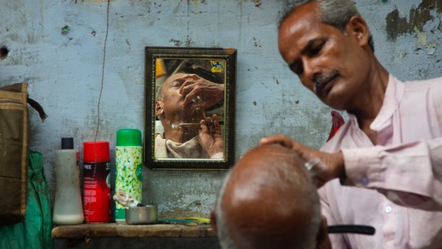 A roadside barber attends to a client in Delhi on Tuesday. Small business owners are hoping Modi will bring better days for India.