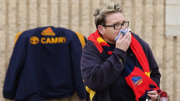 A Crows fan reacts after leaving flowers as a sign of remembrance to the late head coach Phil Walsh.
