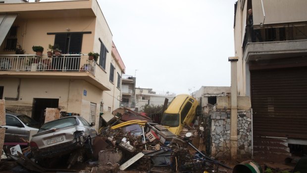 A man, top right, looks out from his home over piles of vehicles after flash floods in Madra, Athens on Wednesday.