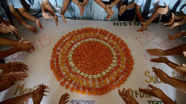 Scvhool children celebrate India's Mars Orbiter Mission by creating a Mars Planet using orange coloured sweets in Ahmedabad.
