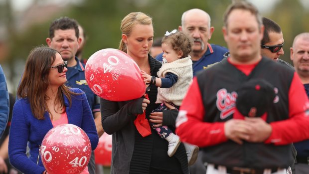 Sarah Harper (centre), the girlfriend of Christopher Lane holds Chris's niece Amelia while Erin Lane, (left) sister of Christopher Lane looks at a memorial game at the Essendon Baseball Club on August 25, 2013.