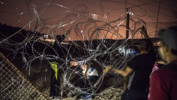 Smugglers guide Palestinians under razor wire as they cross from the West Bank into Israel earlier this month. 