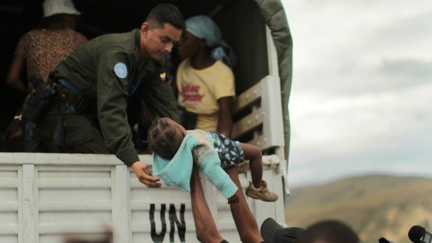  A UN peacekeeper is handed a child during an evacuation of vulnerable residents in Haiti in 2010.