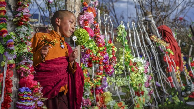 A young nun leaving an area used for eating and socialising on Yarchen Gar. The drab surrounds of the slum are brightened up by forests of plastic flowers.