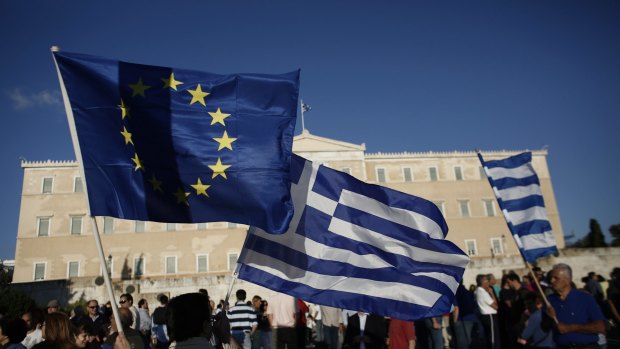 A protester holds a Greek and an EU flag during a pro European Union (EU) demonstration in Athens on Monday. 