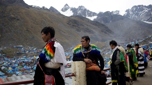 Ukukus, representing mythical creatures, watch a group of dancers perform outside the Sanctuary of the Lord of the Qoyllur Riti. Hundreds of pilgrims tents are seen in the background.