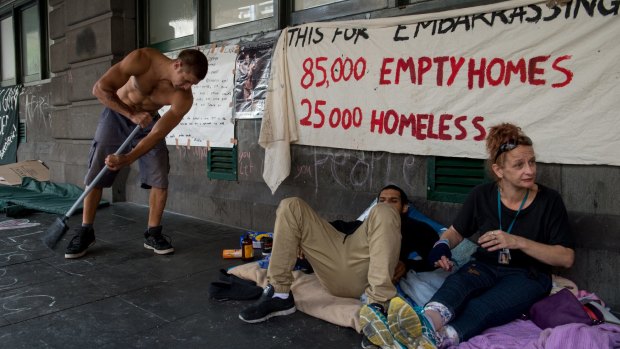 A homeless man keeps the footpath clean outside Flinders street station.