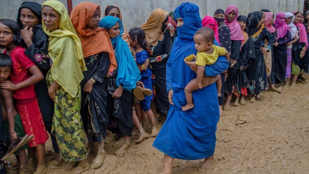 Rohingya women and children wait to collect material for shelters at a refugee camp in Bangladesh.