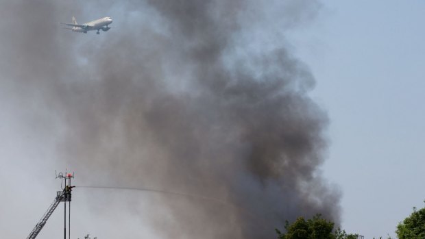 A plane flies past as firefighters work to extinguish a blaze that destroyed a migrant shelter in Dusseldorf on Tuesday. 