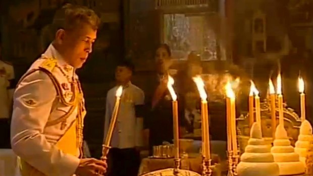 The Thai King lights candles during a religious ceremony at the Grand Palace where the remains of his father lie.