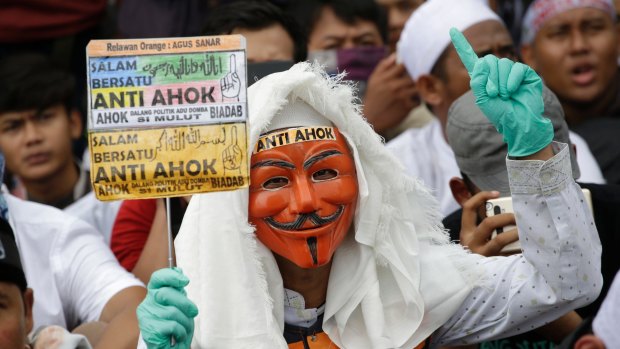 A masked man holds an anti-Ahok sign during a protest against Jakarta's Christian Governor Basuki "Ahok" Tjahaja Purnama.