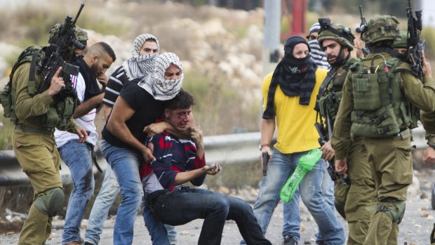 Israeli police provocateurs dressed as Palestinians and Israeli soldiers detain a wounded Palestinian demonstrator during clashes near Ramallah in the Israeli-occupied West Bank.