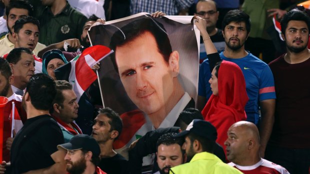 Political minefield: Syrian fans hold a portrait of President Bashar al-Assad in Tehran's Azadi Stadium last month.