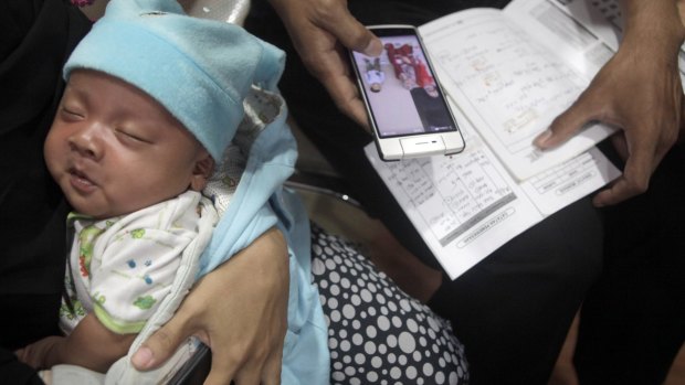 A parent with her child's vaccine record book at Harapan Bunda hospital in Jakarta.