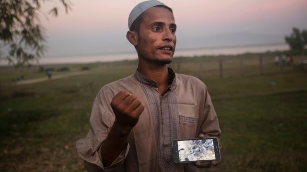 Osman Gani, a Rohingya man from Myanmar, shows a video clip that he shot on his mobile phone while standing on the bank of the Naf River in Bangladesh in December.