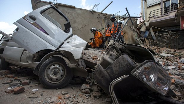 Nepalese military personnel stand on a collapsed building after the earthquake in Kathmandu.